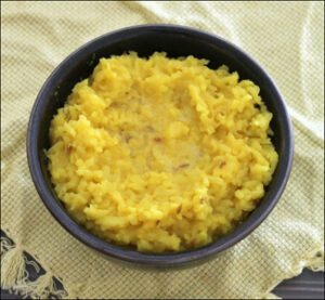 a bowl of hot khichadi being served with simple ingredients like rice, dal, ghee.