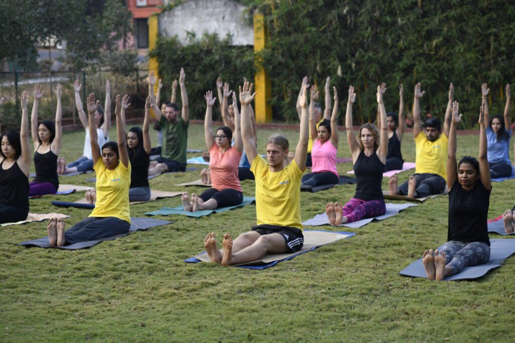 Students practicing yoga asanas in a peaceful garden during the Yoga Holiday at Bharatha Yoga Shala in Mysore. The session focuses on alignment, breath awareness, flexibility, and inner balance.