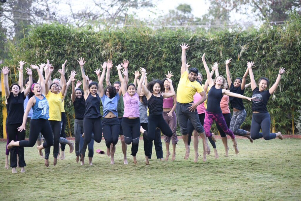 Students jumping with joy in the garden during the Yoga Holiday at Bharatha Yoga Shala in Mysore, embodying health, bliss, and inner freedom through daily traditional practice.