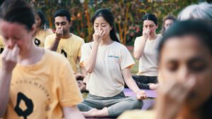 Bharath yoga shala students doing pranayama or breathing exercises outside in garden.