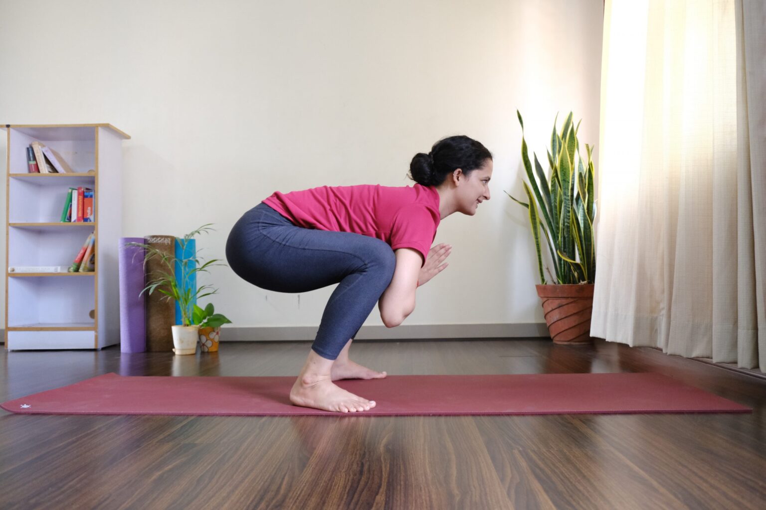a student holding Dhruta Utkatasana, yoga asana that combines a squatting position with a forward bend