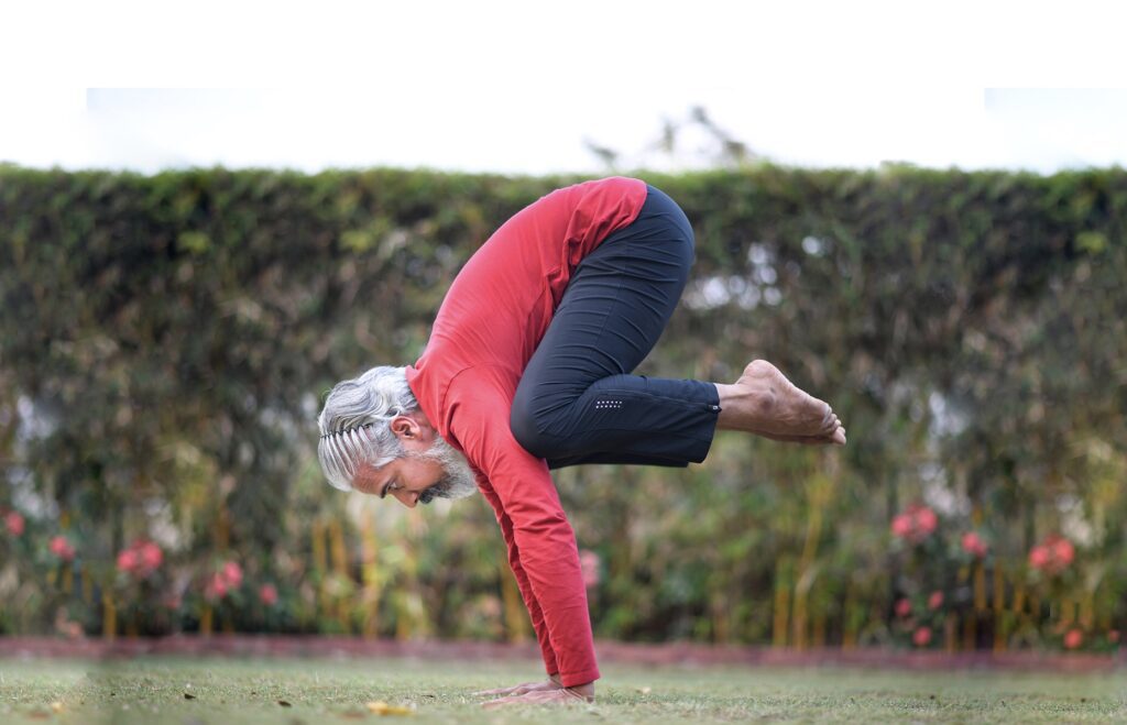 Acharya Bharat Shetty in Bakasana yoga pose. Posing in the garden of Bharatha yoga shala. This is a pose from Asthanga sequence.