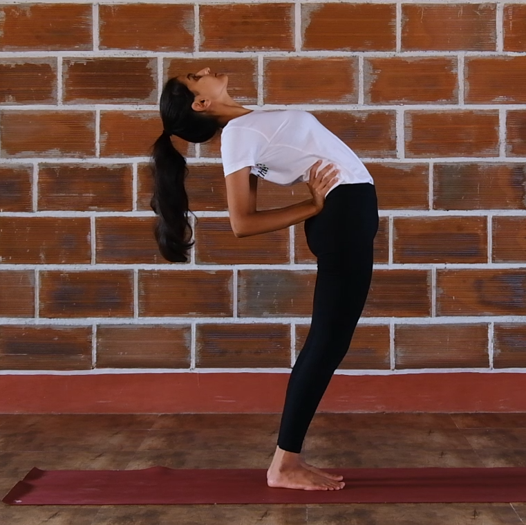 Ardha Chakrasana (The Half Wheel Posture) yoga pose by a young girl in an indoor hall of a yoga school, daily yoga practice