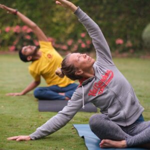 students in Arogyam Program, sitting out in a garden and practicing healing yoga poses
