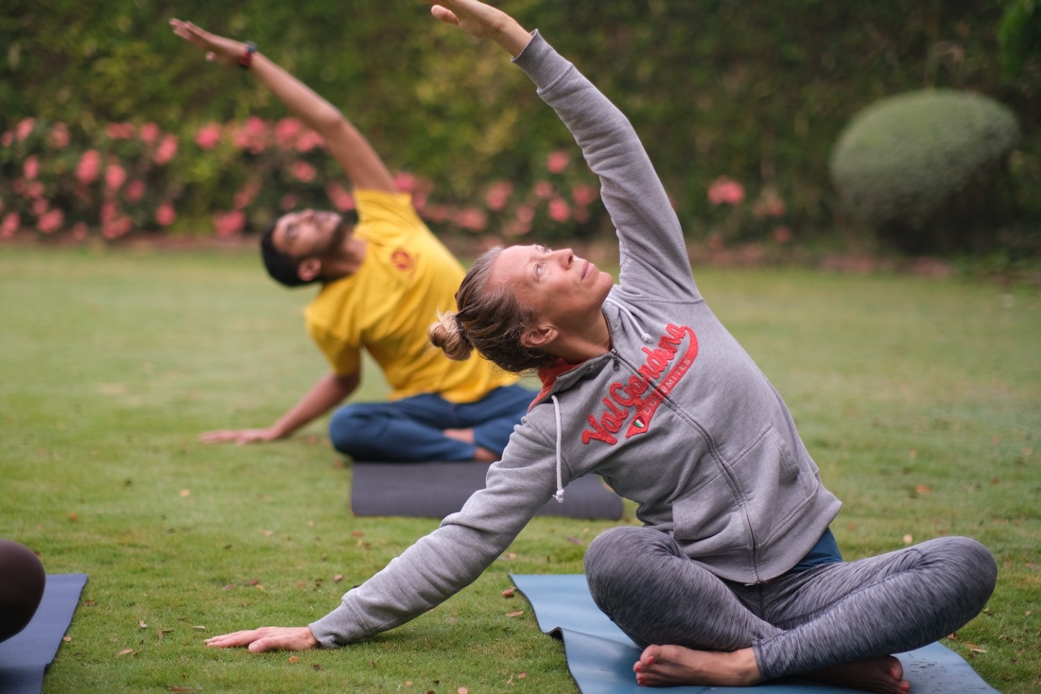 students in Arogyam Program, sitting out in a garden and practicing healing yoga poses